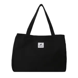 Sac cabas minimaliste en toile noire avec étiquette graphique blanche pour shopping et étudiants