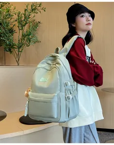 Side view of a mint green water-resistant nylon backpack with plush charm for students