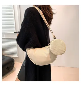 Detail of beige corduroy crescent bag and round pouch shown on model in a modern interior