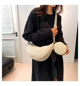 Detail of beige corduroy crescent crossbody bag featuring texture and small round pouch