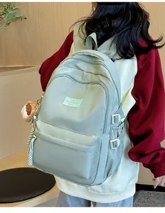 Close-up of mint green nylon backpack with buckle detail and plush bear charm accessory