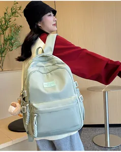 Detail of mint green school backpack with plush pendant and brand label on front