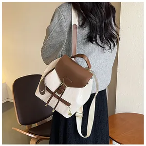 Detalle de mini mochila acolchada con solapa de cuero marrón y colgante con cara sonriente