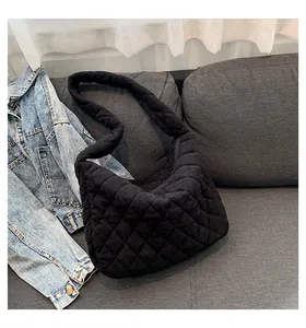 Detail of black corduroy tote bag with diamond quilted pattern on a grey sofa