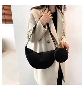 Detail of black corduroy crescent bag showing texture and round coin purse attachment