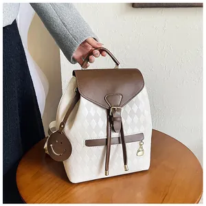 Detail of drawstring bucket backpack with beige diamond quilt and brown leather trim