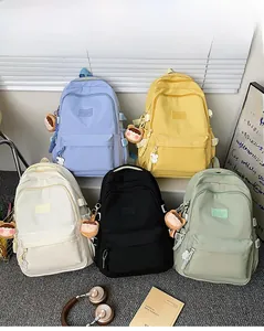 Close-up of five colorful minimalist backpacks featuring plush charms and woven strap details