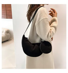 Detail shot of a black corduroy crescent shoulder bag with a round coin pouch on a model