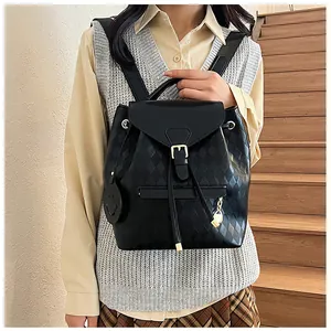 Detail of black quilted bucket backpack with gold buckle and smiley charm on shoulder