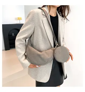 Detail of grey corduroy crescent bag with small round pouch worn on beige blazer