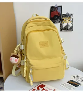 Detail view of a pale yellow school backpack with cute plush charm and durable fabric