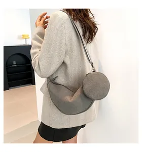 Detail of gray corduroy dumpling crossbody bag with a round coin purse on a model