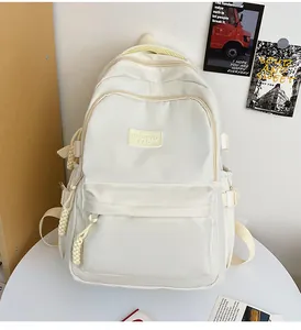 Detailed view of cream oxford backpack featuring branded fabric label and woven zipper pull