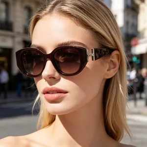 Detail of burgundy cat-eye sunglasses with gradient lenses and gold T-shaped metal hinges
