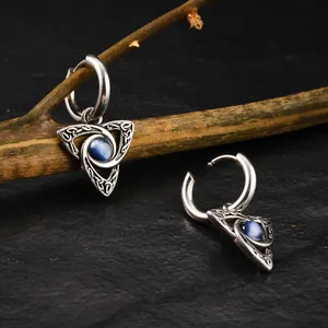 Detailed close-up of men's Celtic knot earrings with blue cat eye stone in vintage silver