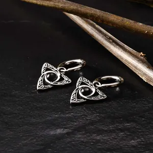 Detail shot of men's Celtic Triquetra earrings with black stone on dark stone surface