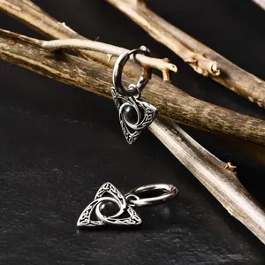 Detailed shot of Celtic knot hoop earrings with black beads on natural wood