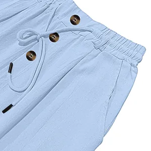Detail of light blue cotton linen trousers showing elastic waist, drawstring and buttons