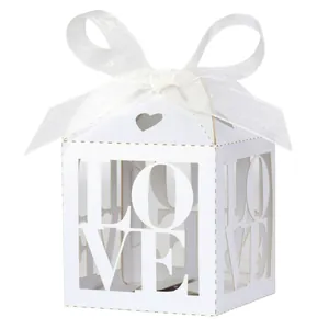 Detailed laser-cut ivory white paper candy box with LOVE lettering and a satin ribbon bow