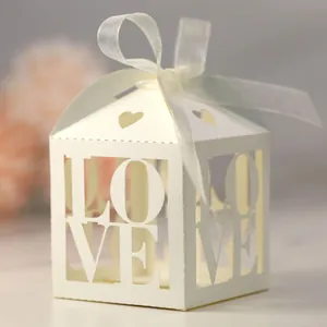 Detail of laser-cut ivory candy box with LOVE hollow design and white ribbon decoration