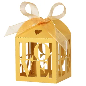 Close-up of golden paper wedding favor box with LOVE hollow-out design and ribbon bow