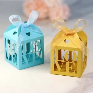 Detail of laser-cut heart and LOVE pattern candy boxes with silk ribbons in blue and yellow