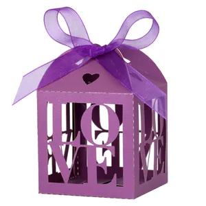 Close-up of purple laser-cut LOVE candy box with ribbon bow for wedding gifts