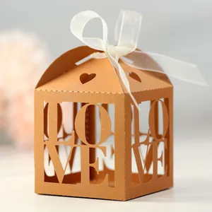 Detail of laser-cut ivory wedding favor box with LOVE pattern and white organza ribbon