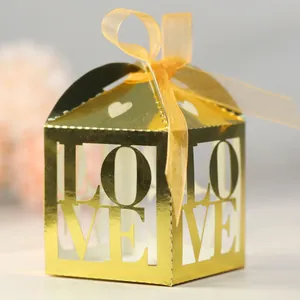 Macro detail of golden mirrored LOVE favor box with elegant orange ribbon bow