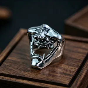 Macro shot of silver metal demon hannya mask ring on a dark wood display base