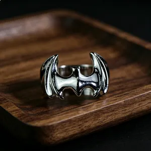 Macro view of silver bat-shaped superhero metal ring on a dark wooden display tray