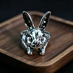 Detailed close-up of a vintage silver rabbit-shaped ring on a dark wooden tray