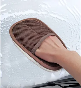 Close-up view of a brown mesh car wash mitt cleaning a soapy white car surface