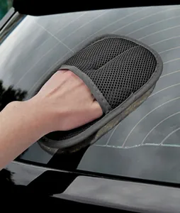 Close-up view of a professional black mesh car wash mitt cleaning a vehicle rear window
