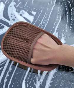 Close-up detail of a brown mesh car wash mitt being used on a soapy vehicle surface