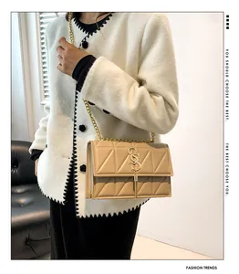 Dettaglio della borsa a tracolla beige trapuntata con catena dorata e pendente