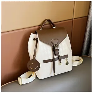 Detail of white quilted backpack with brown leather drawstrings and smiley face charm