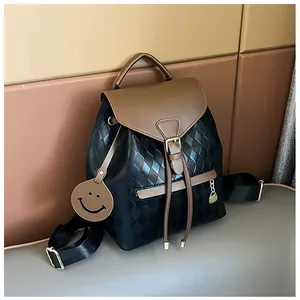 Close-up of black quilted bucket backpack featuring brown leather trim and smiley charm