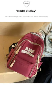 Detail view of burgundy student backpack featuring white embroidered SJM lettering