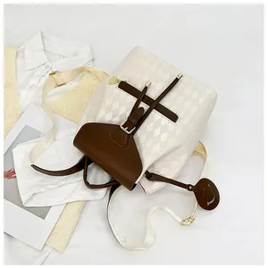 Detailed top view of a quilted drawstring bucket backpack with brown leather flap and smiley charm