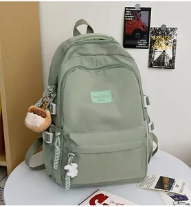 Detail of light green multi-pocket school backpack with cute plush charm and side buckles