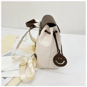 Detail of quilted drawstring backpack featuring brown contrast trim and smile face charm