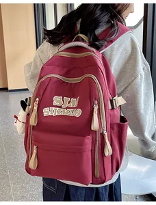 Detail view of burgundy waterproof nylon backpack with SJM logo and plush Snoopy pendant