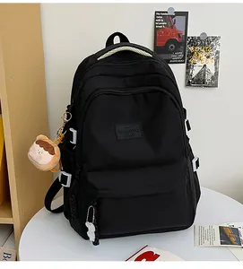 Detail of black school backpack with multiple compartments and cute decorative pendants