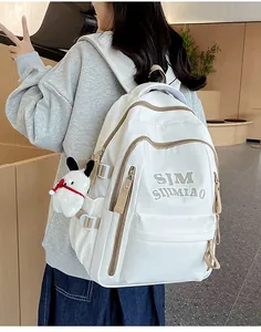 Detail view of white waterproof nylon backpack with brown contrast zippers and plush charm