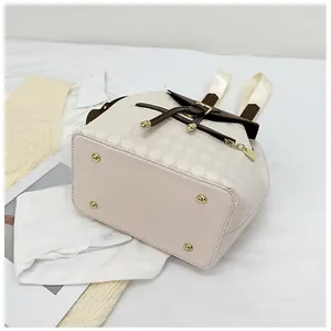 Detail view of cream quilted bucket backpack with brown flap and gold bottom studs
