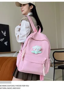 Vue détaillée d'un sac à dos rose en toile avec fleur en peluche et poche latérale à cordon