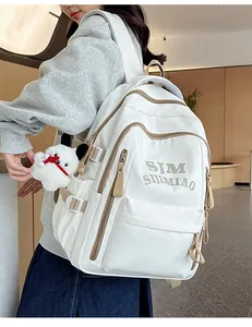 Side view of white and khaki nylon backpack with plush charm on a female model
