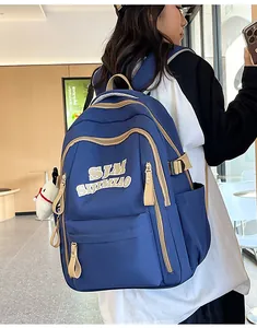 Blue nylon backpack with khaki zipper trim and plush charm shown on female model