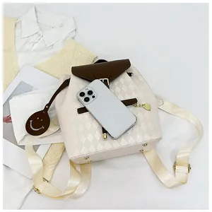 Detail of quilted drawstring backpack with gold buckle and brown leather smiley charm